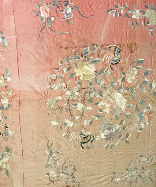 A pair of framed early 20th century Chinese silk embroideries, probably panels cut from a larger embroidery or bed cover. Embroidered with a large central cartouche of flowers birds and butterflies. 89cm x 73cm.
